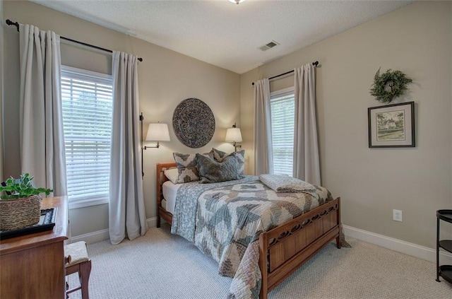 carpeted bedroom with baseboards, visible vents, and multiple windows