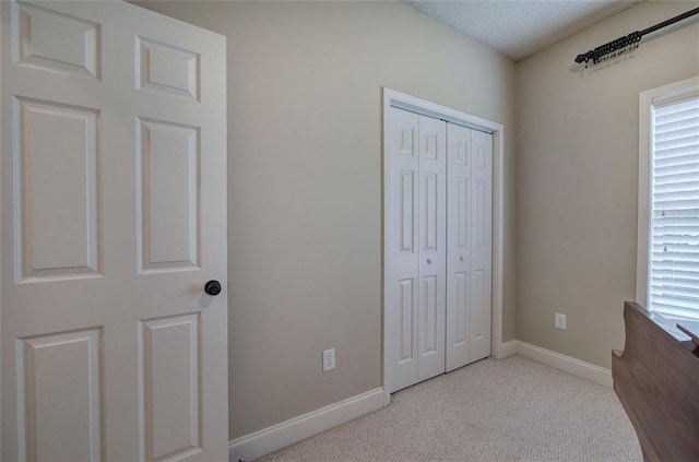 unfurnished bedroom featuring baseboards, carpet flooring, multiple windows, and a closet