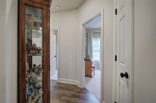 corridor featuring baseboards and dark wood-style floors