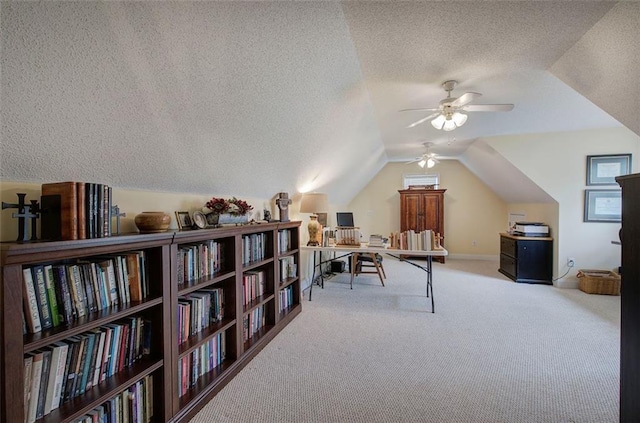 office area with carpet floors, baseboards, a textured ceiling, a ceiling fan, and vaulted ceiling