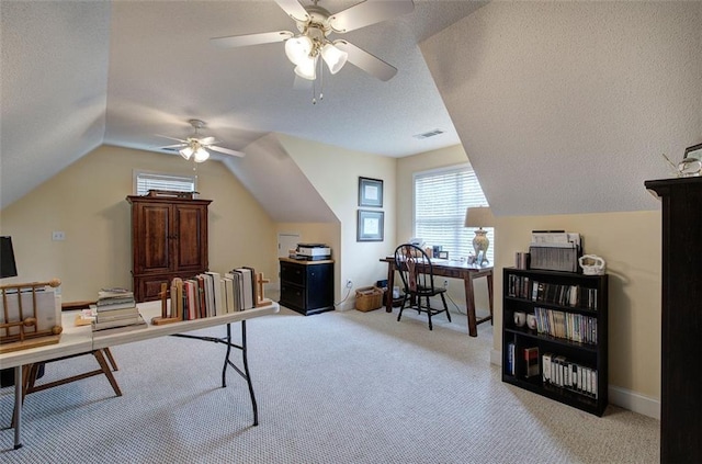 carpeted office space featuring visible vents, a textured ceiling, ceiling fan, and lofted ceiling