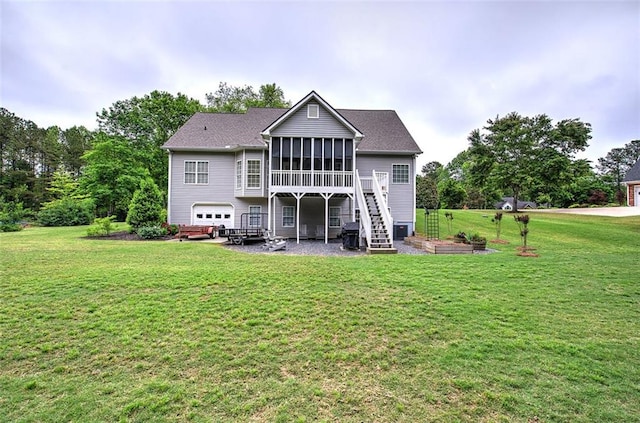 rear view of property with a sunroom, a garage, a lawn, and stairway
