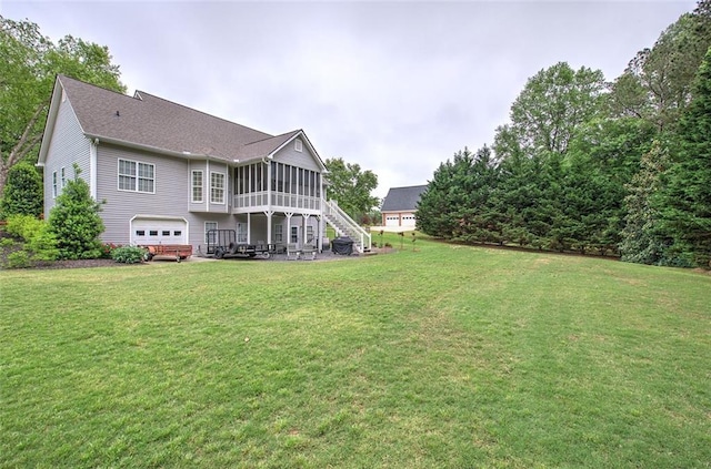 rear view of house featuring a sunroom, a garage, stairs, and a yard
