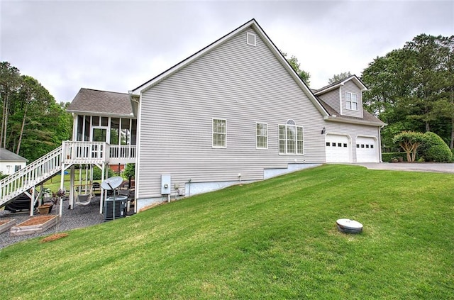 exterior space with central air condition unit, a sunroom, stairway, a lawn, and driveway