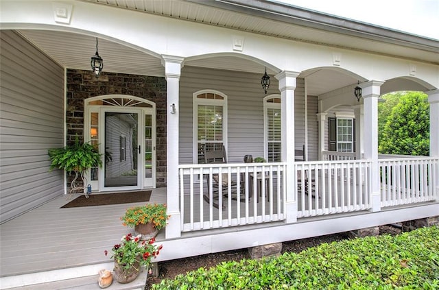 view of exterior entry featuring a porch and stone siding