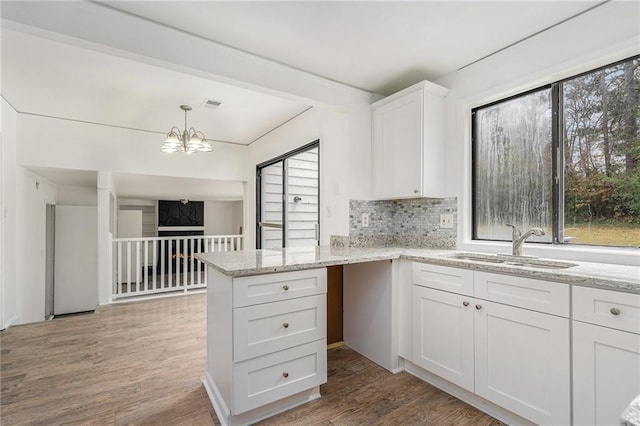 kitchen with sink, tasteful backsplash, light hardwood / wood-style flooring, kitchen peninsula, and white cabinets