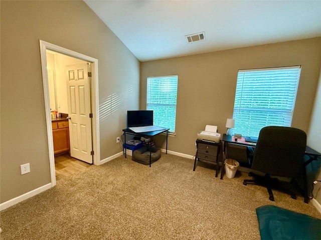 office area with light colored carpet, vaulted ceiling, and baseboards