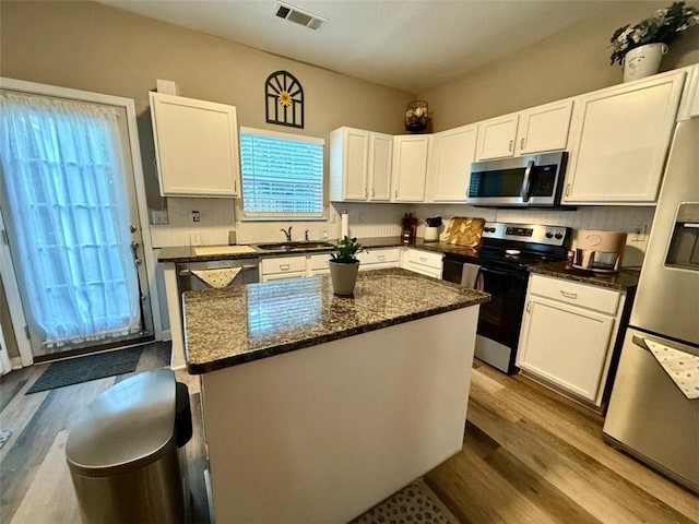 kitchen featuring stainless steel appliances, white cabinets, a center island, and wood finished floors