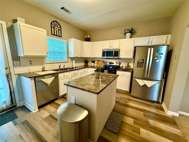kitchen with appliances with stainless steel finishes, white cabinets, and wood finished floors