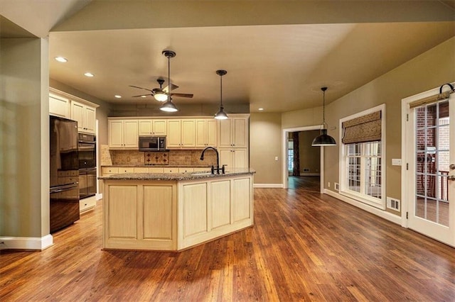 kitchen featuring pendant lighting, an island with sink, sink, backsplash, and ceiling fan