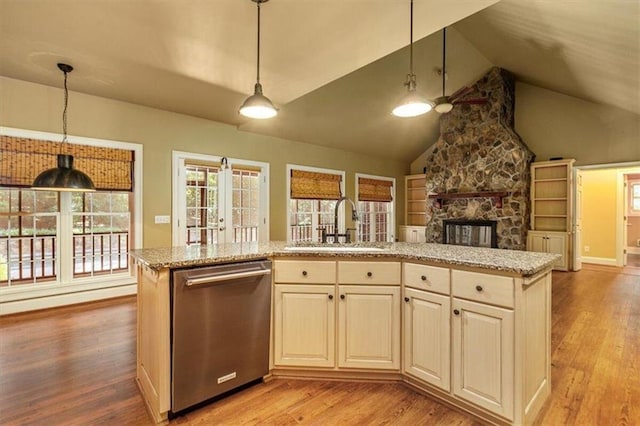 kitchen featuring dishwasher, lofted ceiling, decorative light fixtures, a stone fireplace, and light wood-type flooring