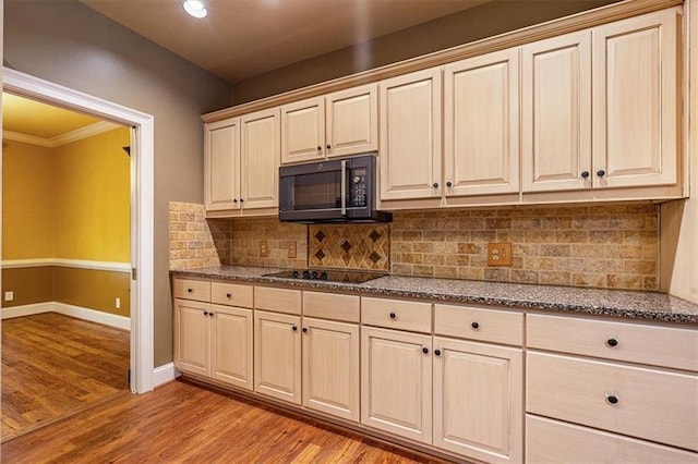 kitchen with light wood-type flooring, decorative backsplash, dark stone counters, and black appliances