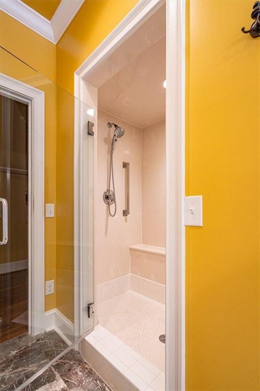 bathroom featuring a shower with door and crown molding