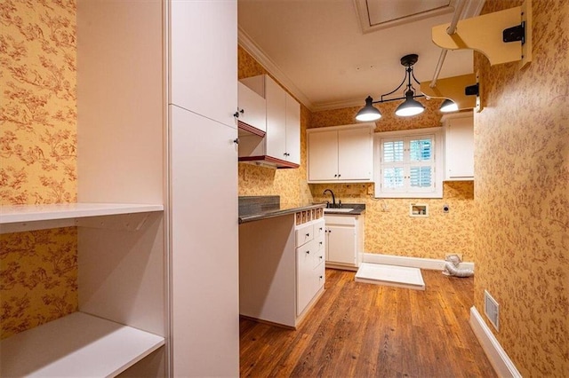 kitchen with white cabinetry, hanging light fixtures, dark hardwood / wood-style floors, and ornamental molding