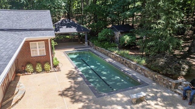 view of pool featuring a shed, a gazebo, and a patio