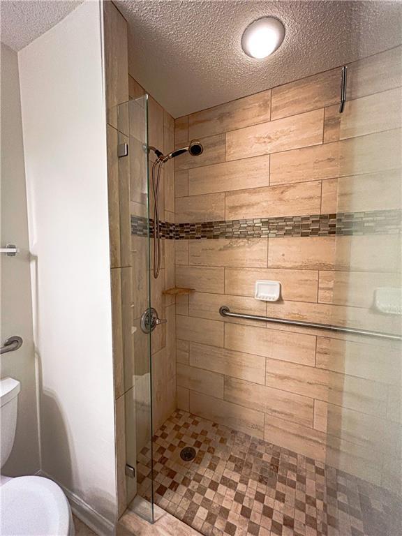 3077 Oakside Cir, Alpharetta, GA 30004 - bathroom featuring a shower stall, a textured ceiling, and toilet