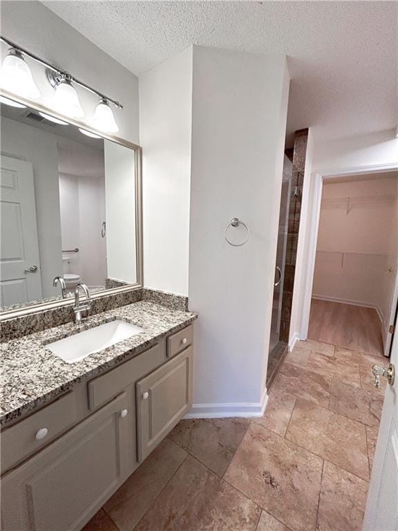 3077 Oakside Cir, Alpharetta, GA 30004 - bathroom featuring a shower stall, vanity, a textured ceiling, a walk in closet, and baseboards