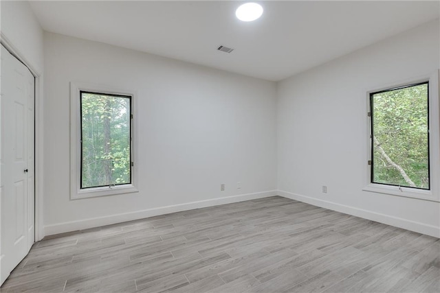 empty room featuring a healthy amount of sunlight and light hardwood / wood-style floors