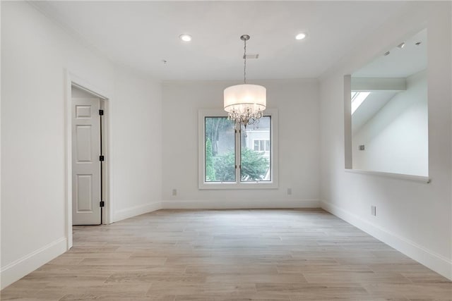 spare room with a skylight, light hardwood / wood-style flooring, and a notable chandelier