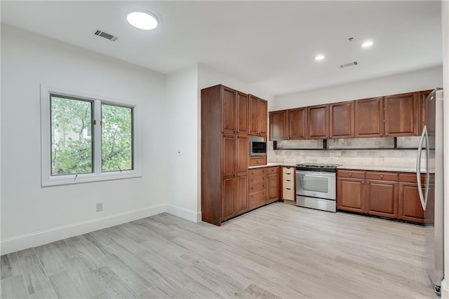 kitchen featuring appliances with stainless steel finishes, light wood-type flooring, and tasteful backsplash