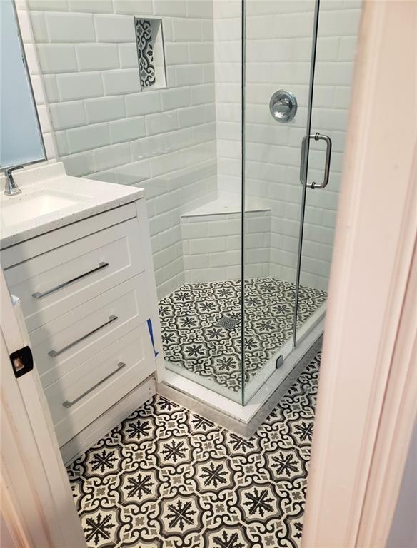 bathroom with a shower with shower door and sink