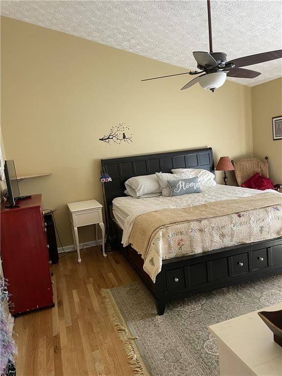 bedroom with ceiling fan, a textured ceiling, and hardwood / wood-style flooring