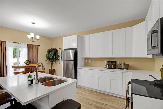 kitchen with appliances with stainless steel finishes, a breakfast bar, pendant lighting, sink, and white cabinets