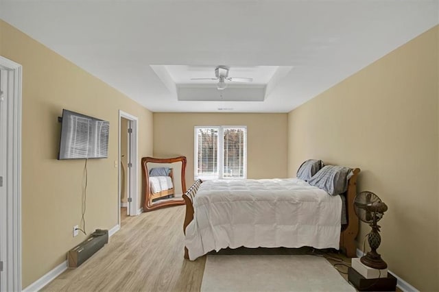 bedroom with a tray ceiling, light hardwood / wood-style floors, and ceiling fan