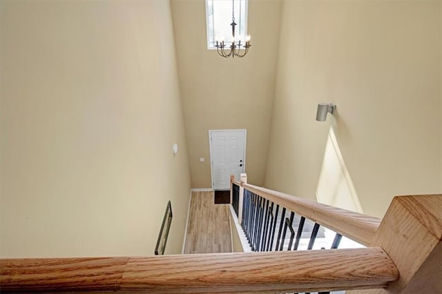 stairs with hardwood / wood-style floors and a notable chandelier