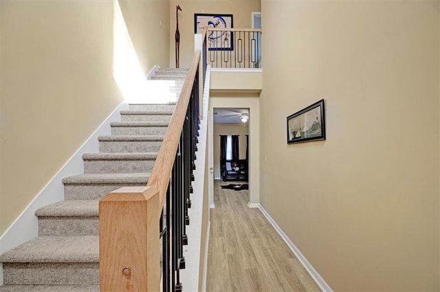 stairway with hardwood / wood-style floors and a high ceiling