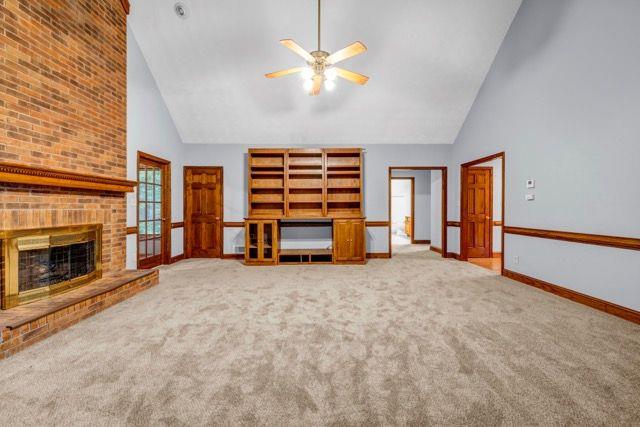362 Clyde Ct, Mcdonough, GA 30252 - unfurnished living room with high vaulted ceiling, ceiling fan, carpet flooring, baseboards, and a fireplace