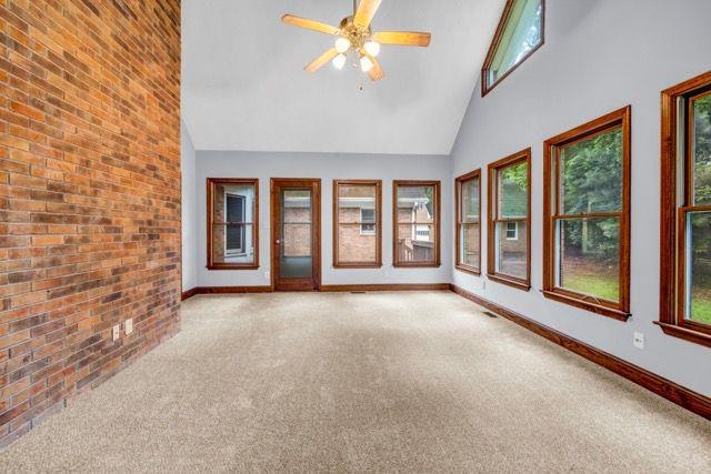 362 Clyde Ct, Mcdonough, GA 30252 - spare room with carpet flooring, healthy amount of natural light, baseboards, high vaulted ceiling, and brick wall