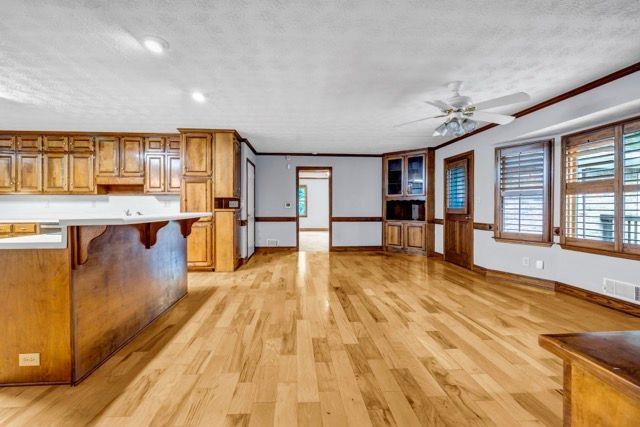362 Clyde Ct, Mcdonough, GA 30252 - kitchen featuring brown cabinetry, a breakfast bar, a textured ceiling, light countertops, and light wood-style floors