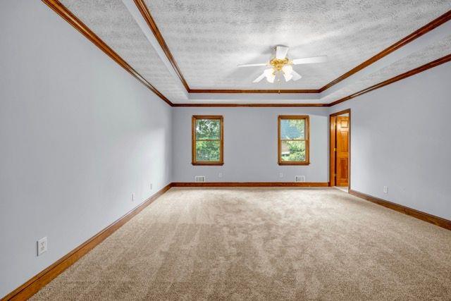 362 Clyde Ct, Mcdonough, GA 30252 - empty room featuring a raised ceiling, ceiling fan, crown molding, carpet, and a textured ceiling