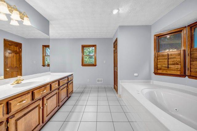 362 Clyde Ct, Mcdonough, GA 30252 - full bath with vanity, a textured ceiling, a whirlpool tub, and tile patterned flooring