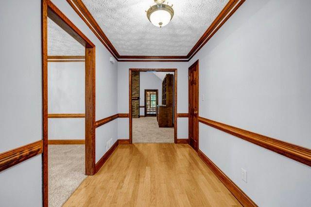 362 Clyde Ct, Mcdonough, GA 30252 - hallway featuring a textured ceiling, ornamental molding, light wood-style floors, baseboards, and light colored carpet