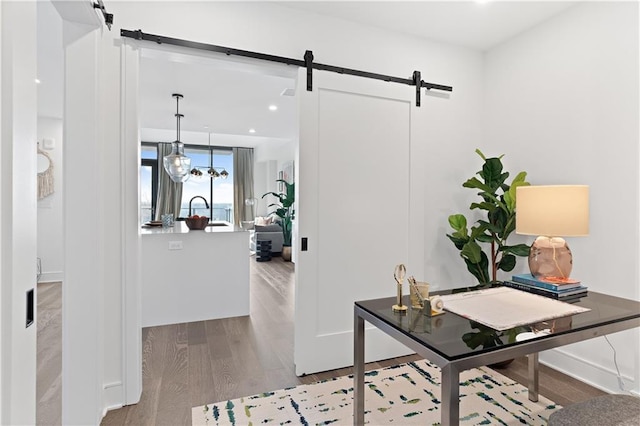 office area featuring light wood-type flooring, a barn door, and a chandelier