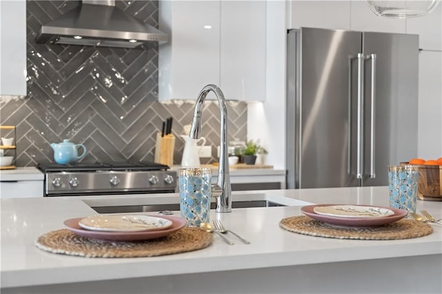 details featuring backsplash, wall chimney exhaust hood, and high end fridge