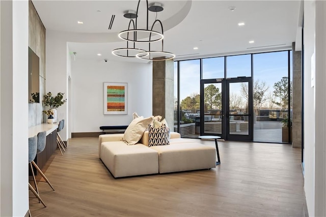 bedroom featuring a notable chandelier, french doors, floor to ceiling windows, light hardwood / wood-style flooring, and access to outside