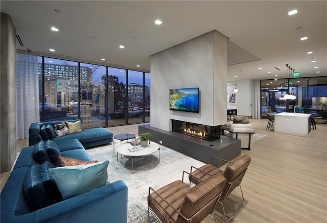 living room featuring floor to ceiling windows, light wood-type flooring, sink, and a large fireplace