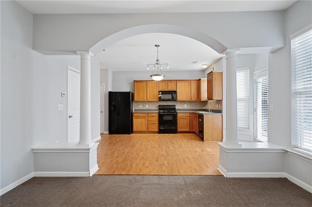 kitchen featuring backsplash, pendant lighting, black appliances, a healthy amount of sunlight, and light carpet