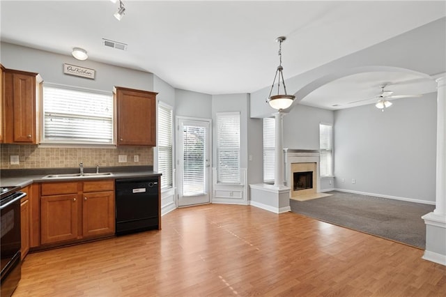 kitchen with a high end fireplace, black appliances, sink, ceiling fan, and light hardwood / wood-style flooring