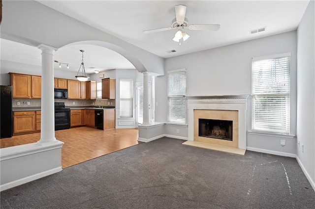 unfurnished living room with ceiling fan, dark carpet, and a wealth of natural light