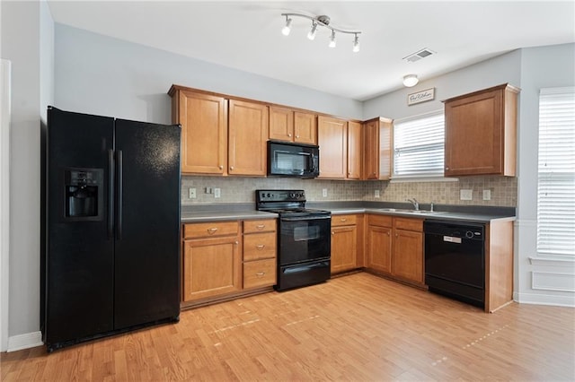 kitchen with decorative backsplash, sink, black appliances, and light hardwood / wood-style flooring