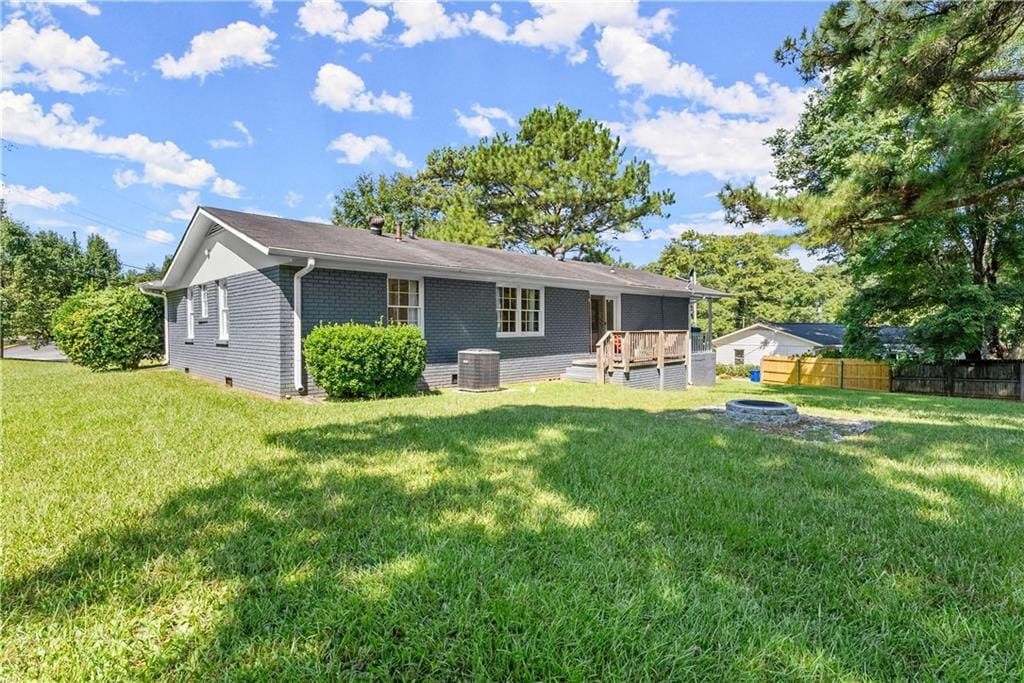 back of house featuring an outdoor fire pit, a yard, and central AC unit