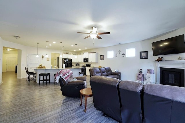 living room featuring dark wood-type flooring and ceiling fan