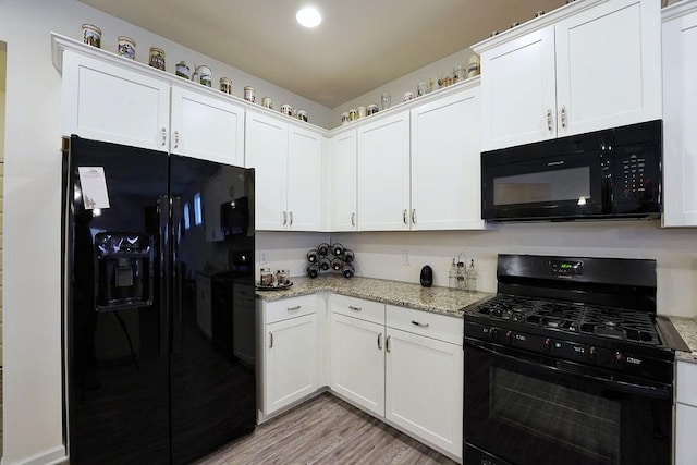 kitchen with white cabinets, light stone countertops, light hardwood / wood-style flooring, and black appliances