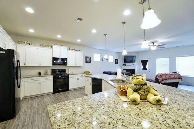 kitchen with white cabinetry, decorative light fixtures, sink, and black appliances