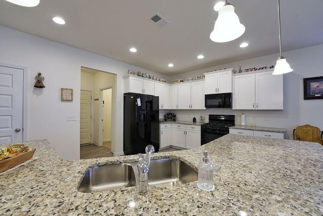 kitchen with white cabinetry, decorative light fixtures, sink, and black appliances