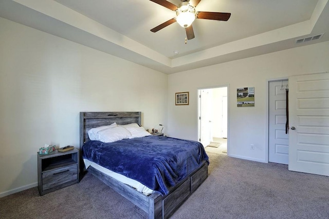 bedroom with a tray ceiling, ceiling fan, and carpet flooring